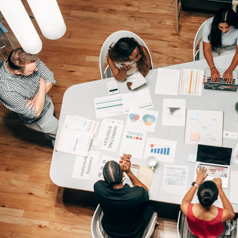 Workers in a modern office environment, sitting around a table, collabourating