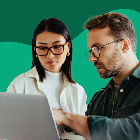Man and woman, looking busines-like, looking at a laptop together
