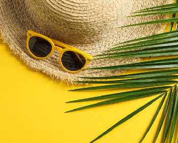 Sun hat, sunglasses, and palm leaf - evoking holidays